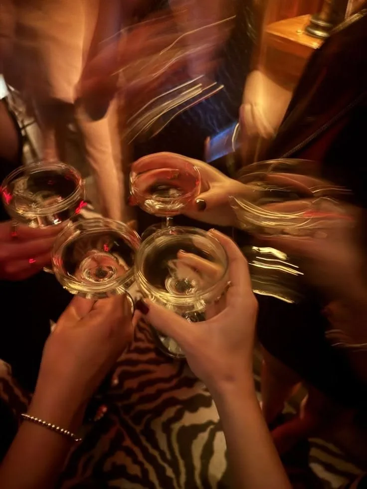 Women raising coupe glasses in motion